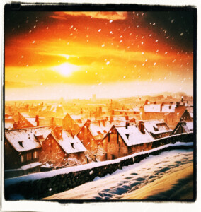 Picture of snow falling during a deep red sun sunrise. Clothes and scene appropriate to the 16th Century France.